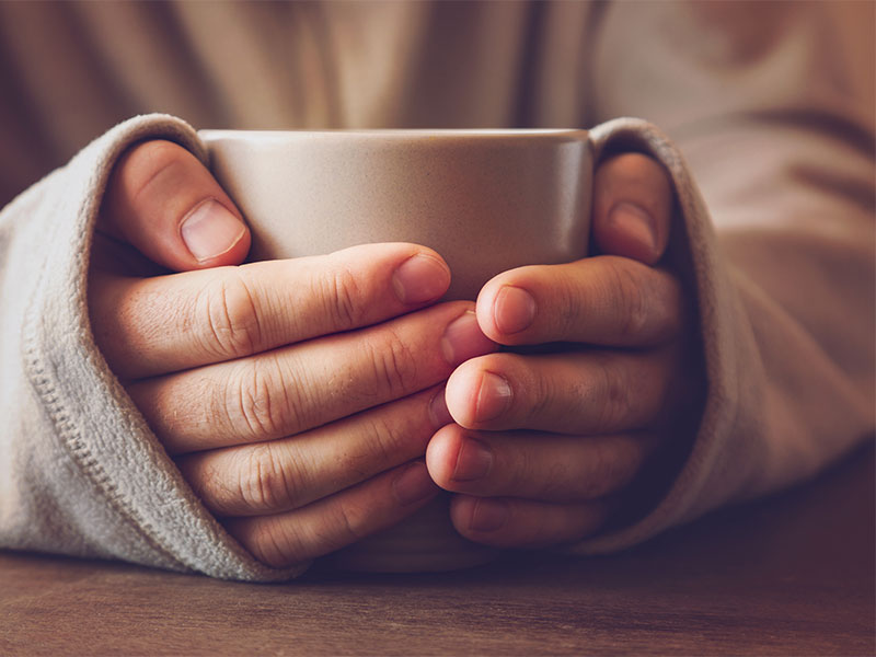 hände wärmen sich an einer Tasse